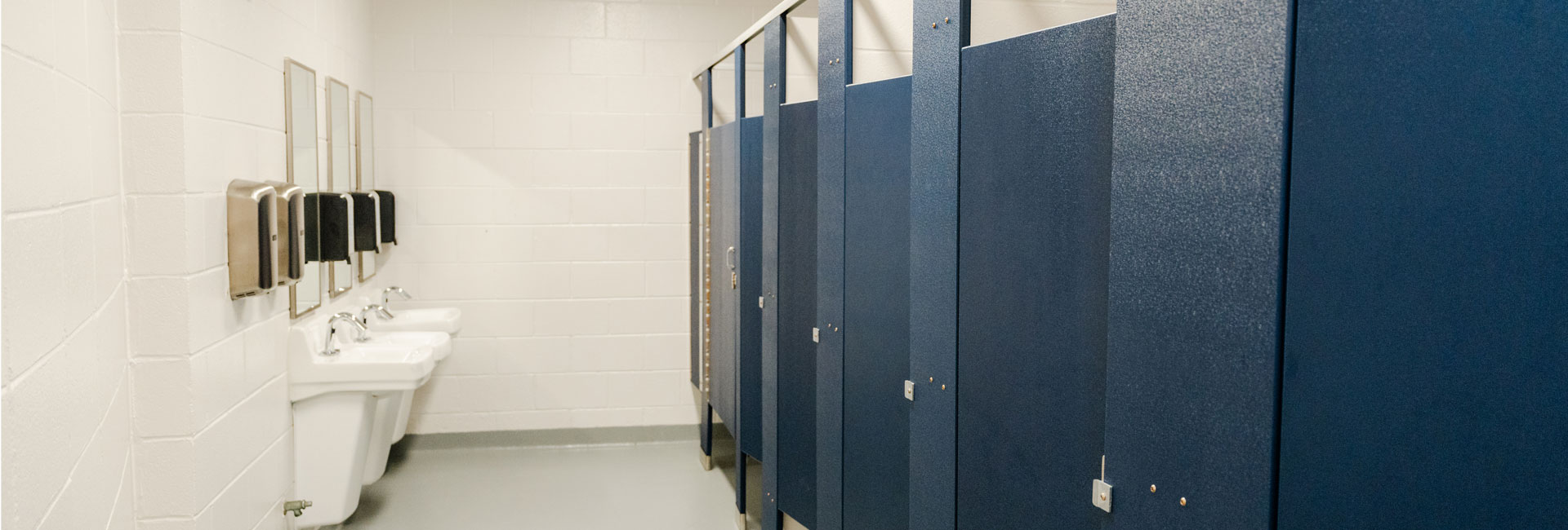 blue bathroom stall doors, white sinks with mirrors above at the Beaufort County School District Whale Branch Middle School